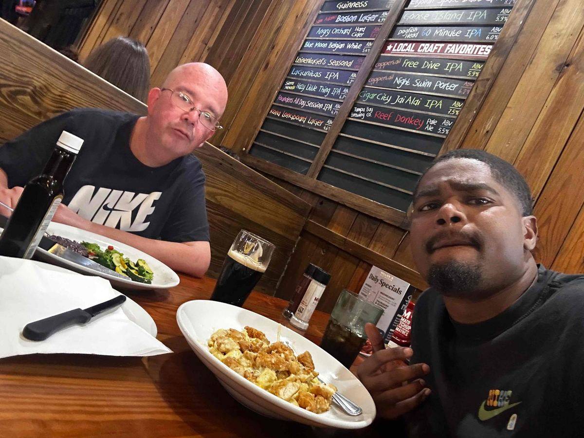A staff member and a man he supports sharing dinner at a restaurant