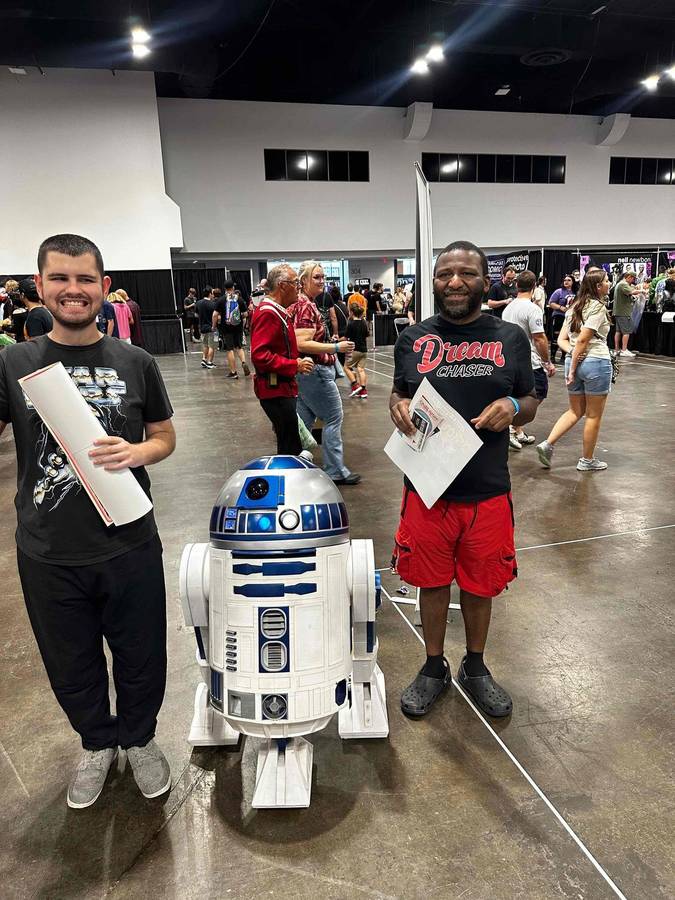Two participants posing beside an R2-D2 replica