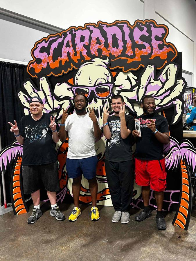 A group posing in front of a colorful Scaradise mural